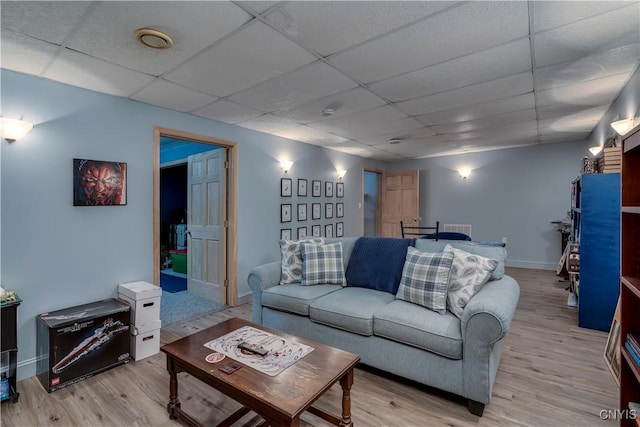 living room with a drop ceiling and light wood-type flooring