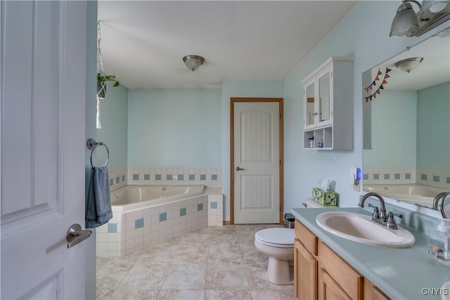 bathroom with tile patterned flooring, vanity, a relaxing tiled tub, and toilet