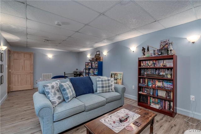 living room with a paneled ceiling and light hardwood / wood-style floors