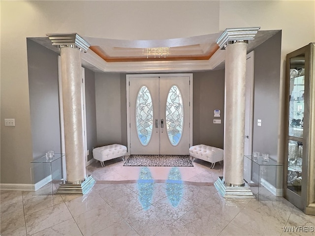 entrance foyer with crown molding, a tray ceiling, and decorative columns