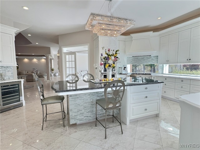 kitchen featuring a kitchen island, white cabinets, custom range hood, wine cooler, and a breakfast bar