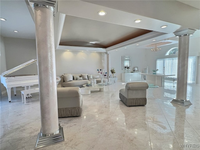 living room with ornate columns, an inviting chandelier, and a raised ceiling