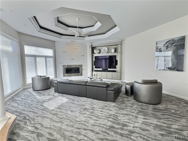 living room with a tiled fireplace and a raised ceiling