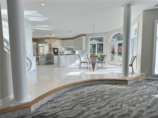 interior space featuring french doors, a notable chandelier, and decorative columns