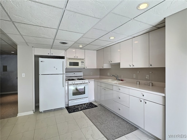 kitchen with sink, white cabinetry, a drop ceiling, and white appliances