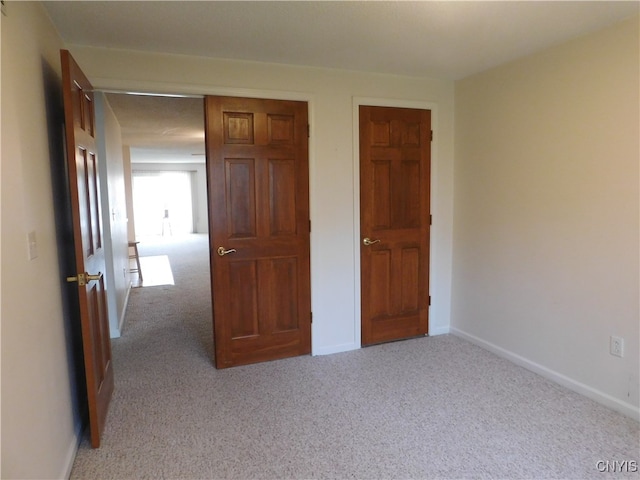 unfurnished bedroom with light carpet and a closet