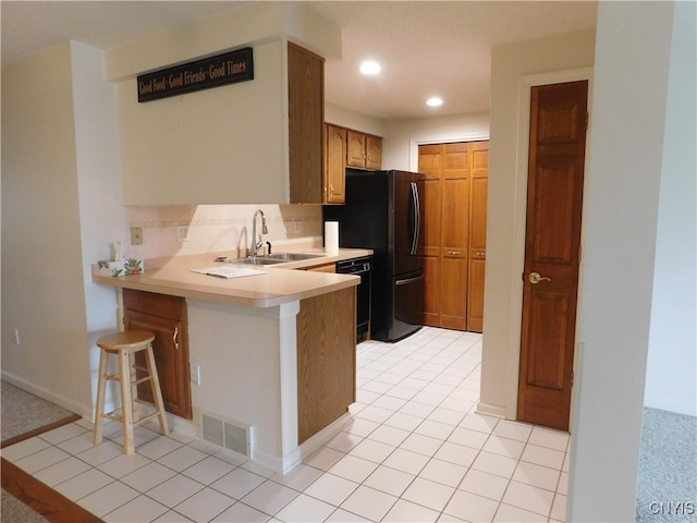 kitchen featuring decorative backsplash, kitchen peninsula, black appliances, sink, and a breakfast bar