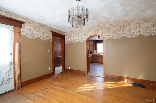 spare room featuring sink, a notable chandelier, and light hardwood / wood-style floors