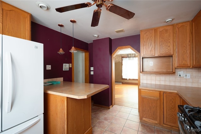 kitchen with kitchen peninsula, ceiling fan, backsplash, stainless steel range oven, and white refrigerator