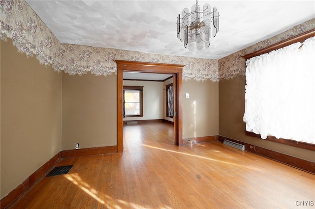 spare room with a chandelier and hardwood / wood-style flooring