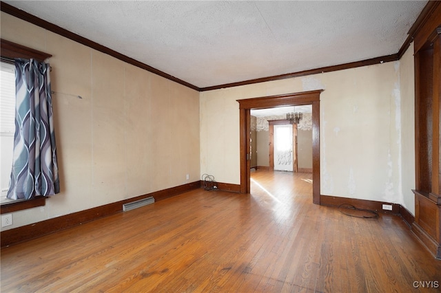 spare room with ornamental molding, a textured ceiling, and hardwood / wood-style flooring