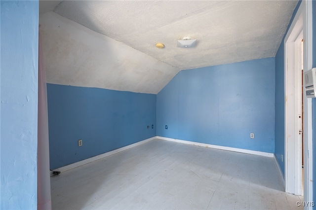 bonus room with lofted ceiling and a textured ceiling