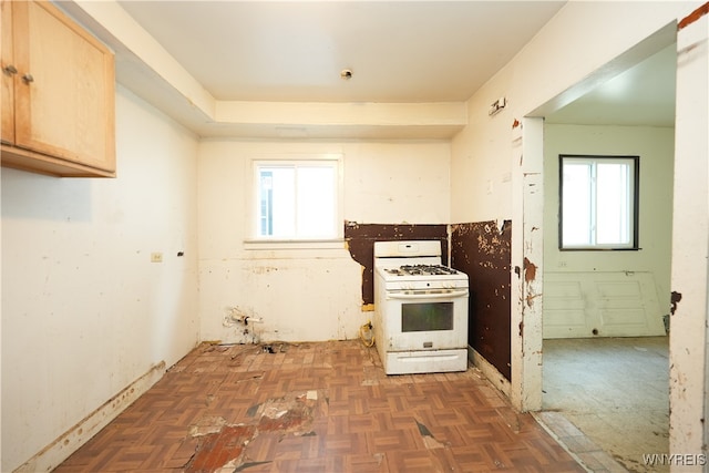 kitchen featuring light brown cabinetry, plenty of natural light, dark parquet floors, and gas range gas stove