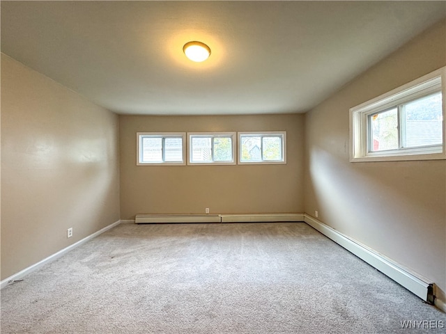 carpeted empty room featuring a wealth of natural light and baseboard heating