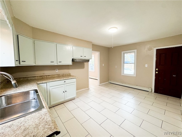 kitchen featuring light tile patterned floors, sink, baseboard heating, and white cabinets