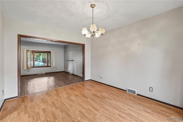 unfurnished room featuring an inviting chandelier and light hardwood / wood-style floors