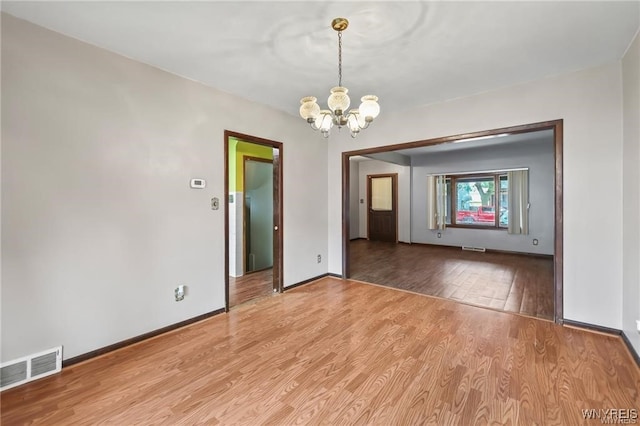 spare room featuring a notable chandelier and hardwood / wood-style flooring