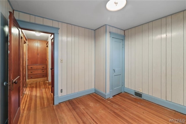 hallway featuring light hardwood / wood-style floors and wooden walls