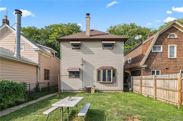 rear view of house with central AC and a lawn