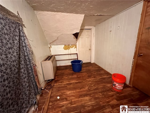 hall with hardwood / wood-style floors, radiator heating unit, and wooden walls