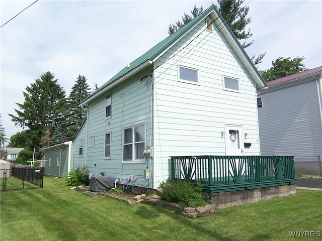 back of property featuring a deck and a lawn