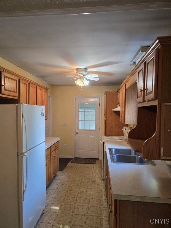 kitchen featuring white fridge, ceiling fan, sink, and stove