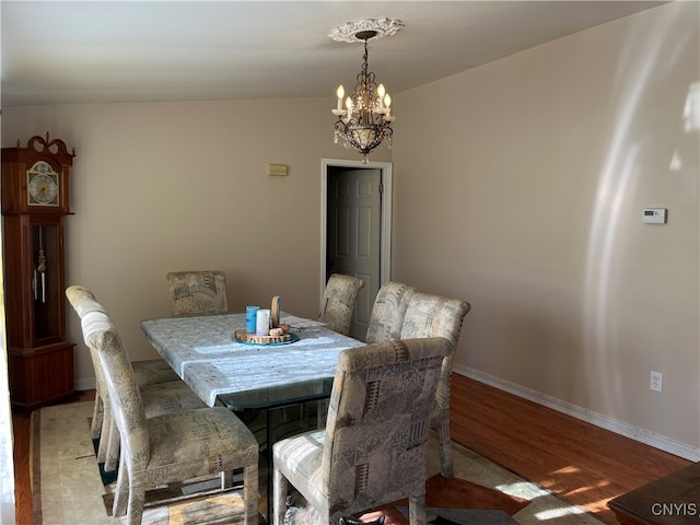 dining area with light hardwood / wood-style floors, lofted ceiling, and an inviting chandelier