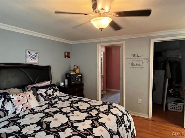 bedroom featuring hardwood / wood-style floors, ceiling fan, a spacious closet, ornamental molding, and a closet