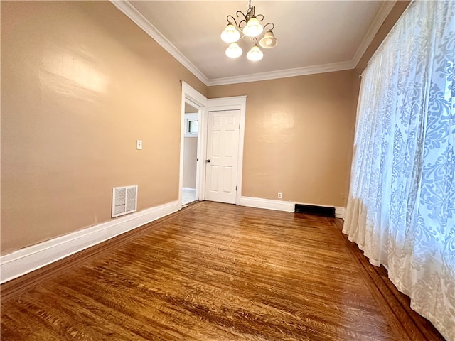 spare room featuring a notable chandelier, ornamental molding, and dark hardwood / wood-style floors