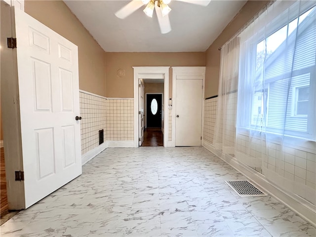 unfurnished room with tile walls and ceiling fan