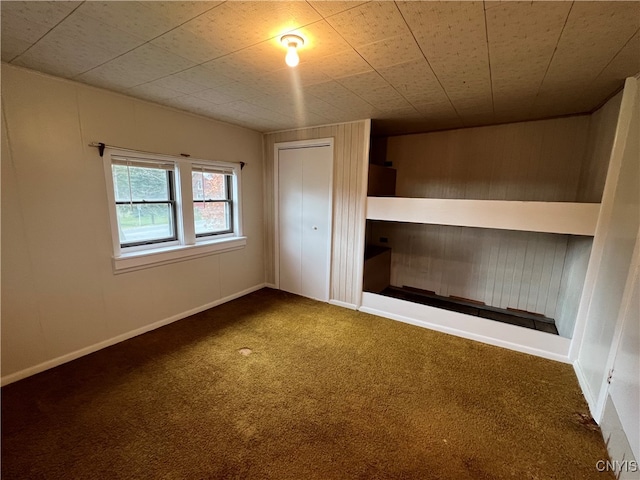 unfurnished bedroom with wood walls and carpet