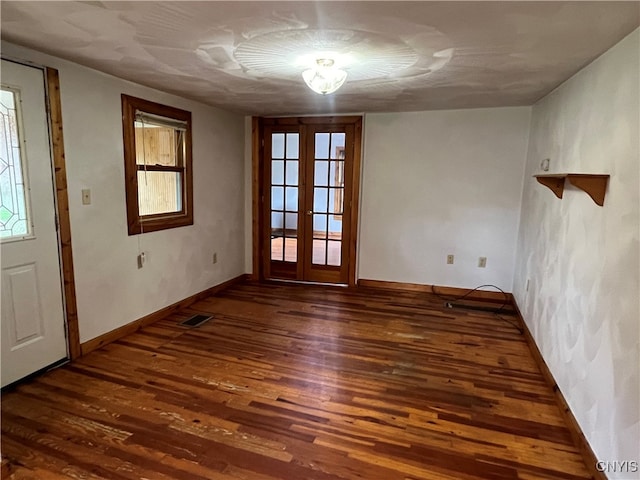 empty room featuring french doors and dark wood-type flooring