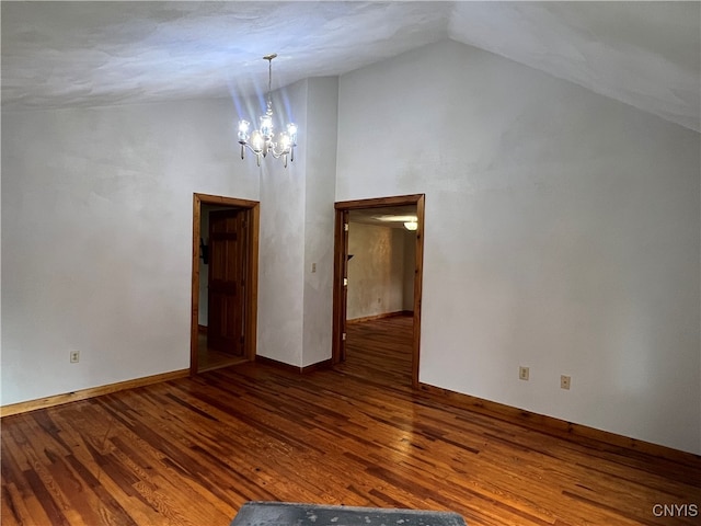 empty room with lofted ceiling, hardwood / wood-style flooring, and an inviting chandelier