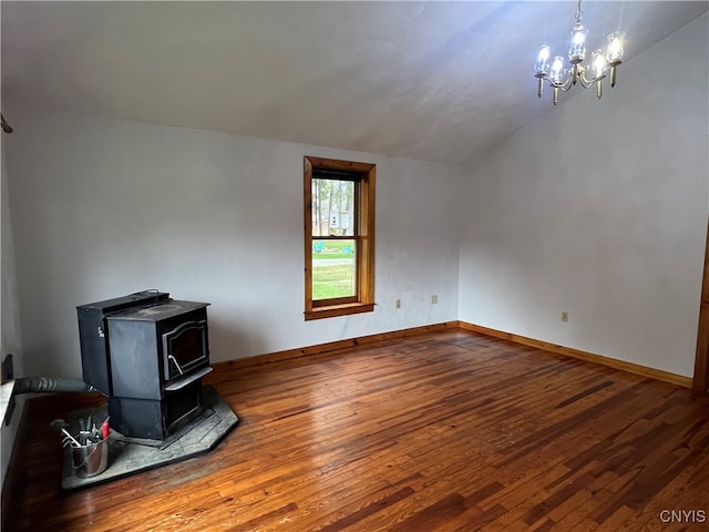 living room with an inviting chandelier, a wood stove, hardwood / wood-style floors, and vaulted ceiling