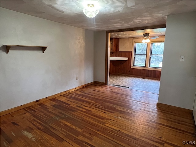 interior space with wood walls, wood-type flooring, and ceiling fan