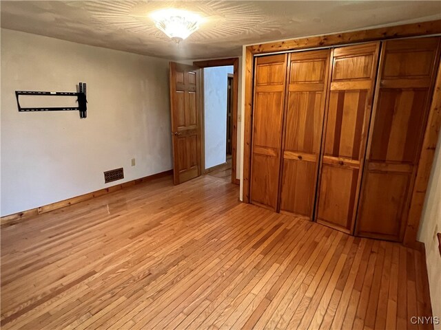 unfurnished bedroom with a closet and light hardwood / wood-style flooring