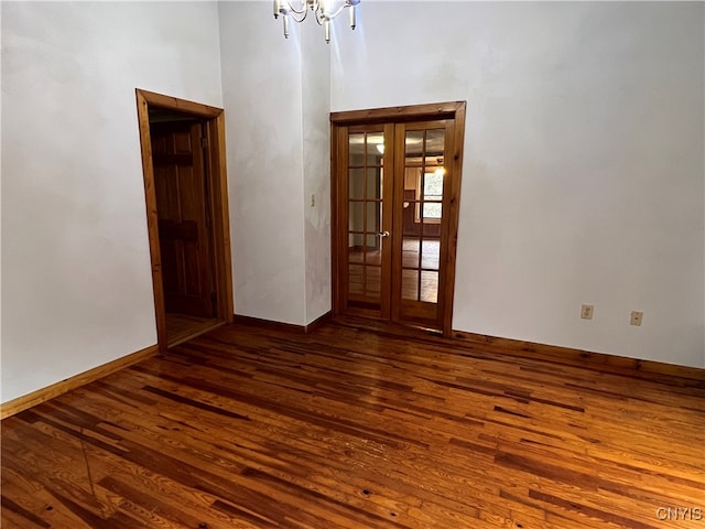 spare room with french doors, a chandelier, and dark hardwood / wood-style flooring