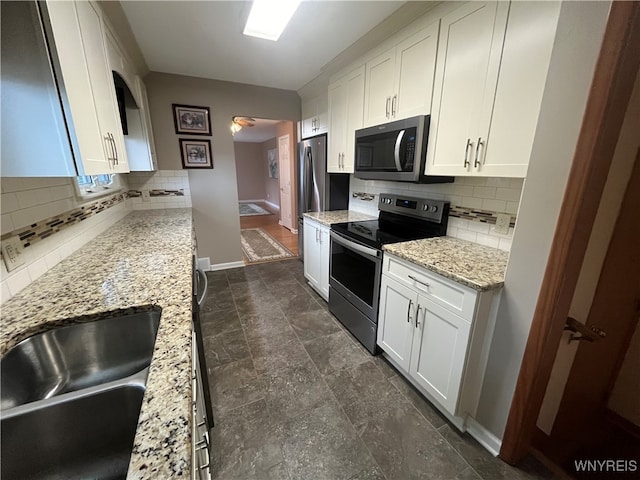 kitchen with light stone counters, tasteful backsplash, appliances with stainless steel finishes, and white cabinets