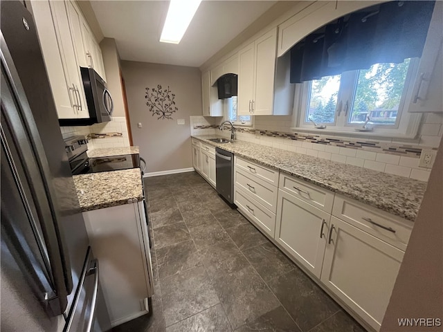 kitchen with decorative backsplash, white cabinets, light stone countertops, and stainless steel appliances