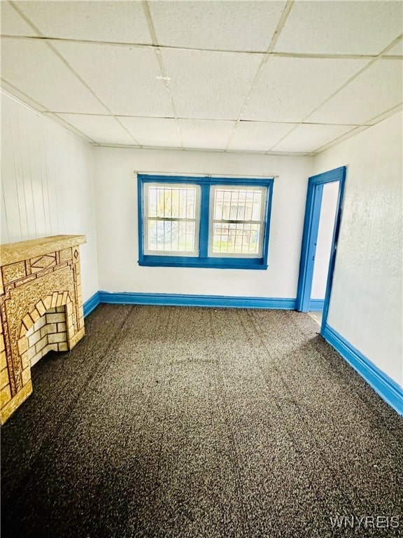 interior space with a stone fireplace and a drop ceiling