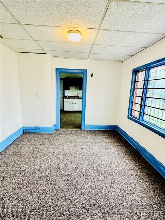 carpeted empty room with a paneled ceiling