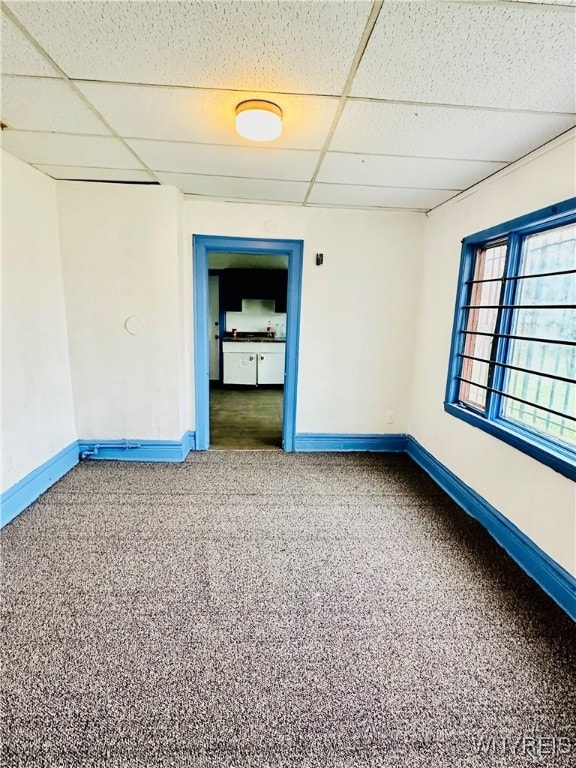 carpeted empty room featuring a drop ceiling