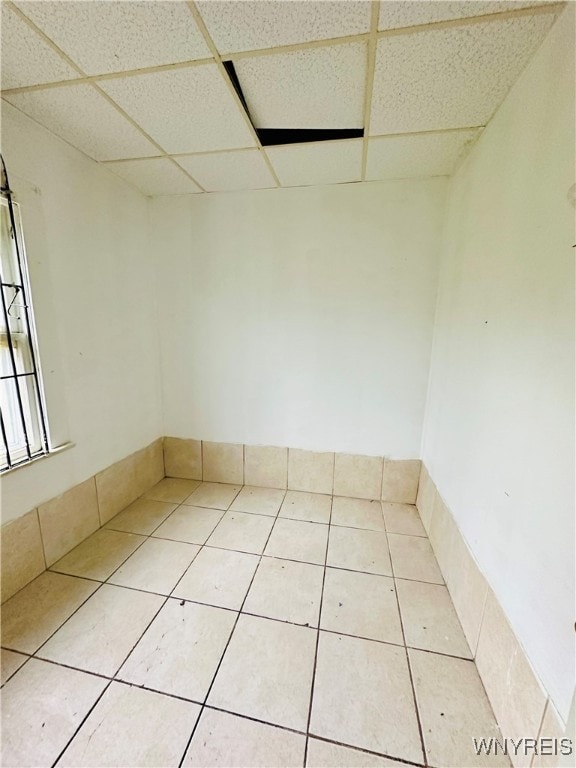 unfurnished room featuring a drop ceiling and tile patterned flooring