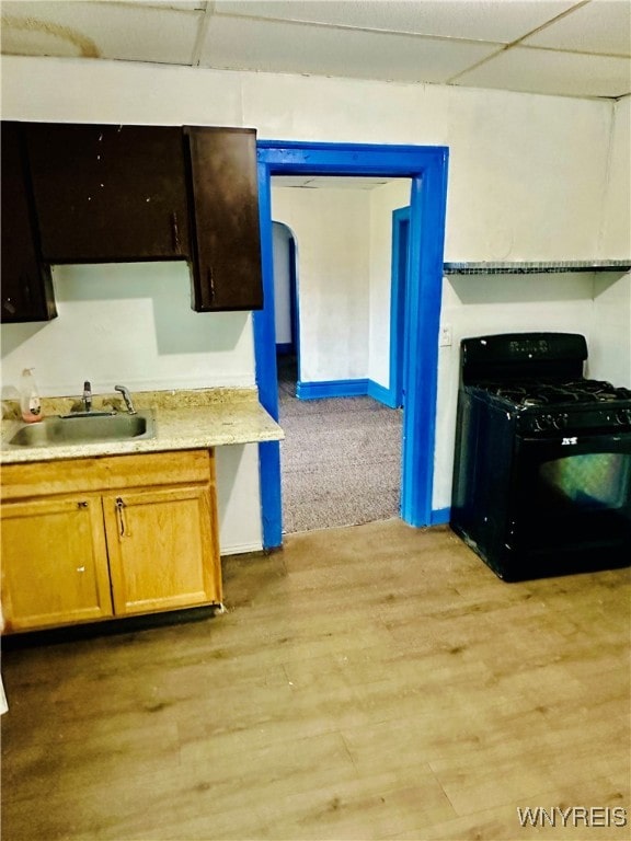 kitchen featuring sink, a drop ceiling, light wood-type flooring, and black gas range oven