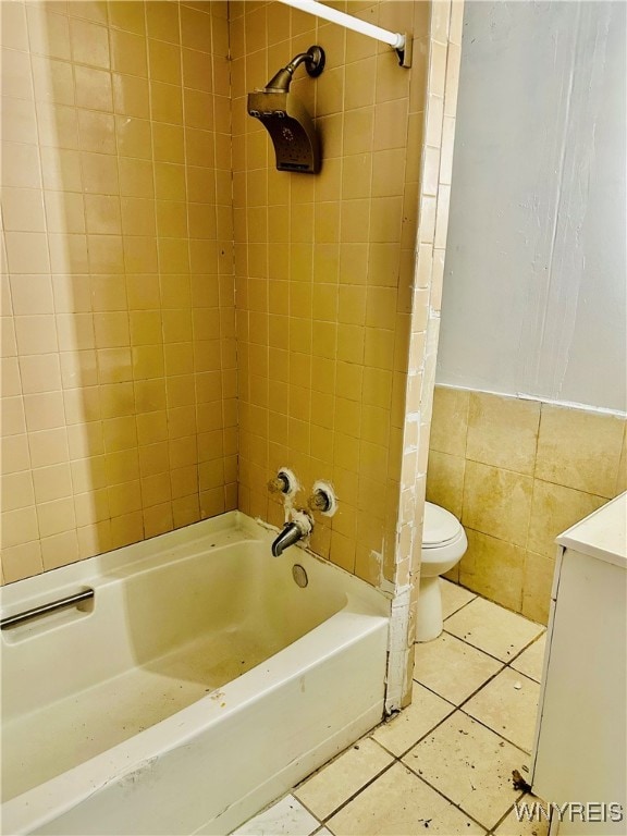 full bathroom featuring tile walls, toilet, vanity, tiled shower / bath combo, and tile patterned flooring