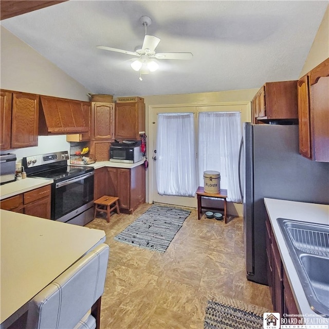 kitchen with ceiling fan, appliances with stainless steel finishes, premium range hood, vaulted ceiling, and sink