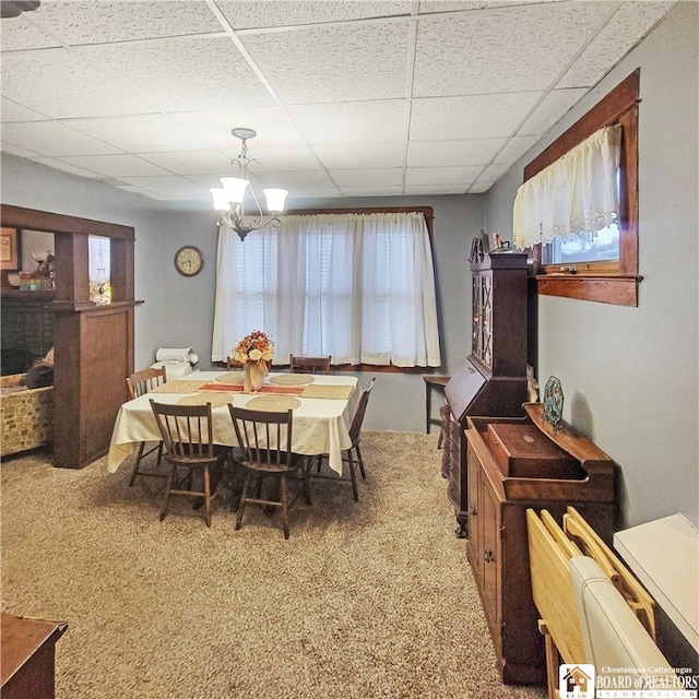 carpeted dining area with a paneled ceiling and a chandelier