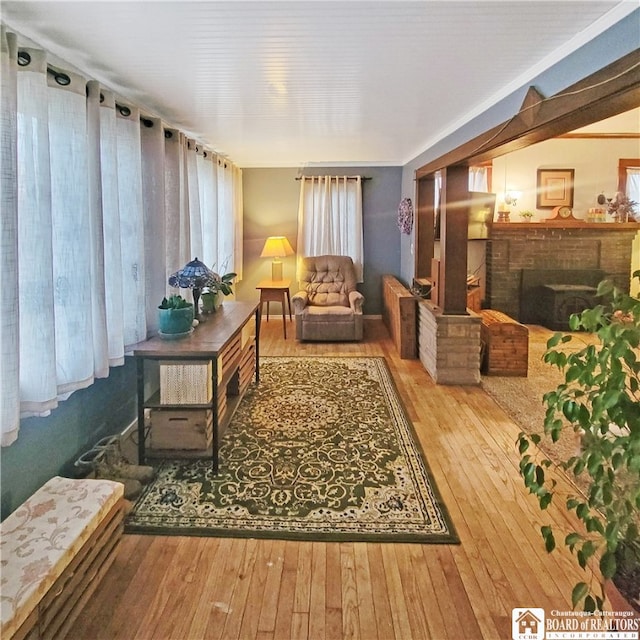 living area with hardwood / wood-style flooring and a brick fireplace