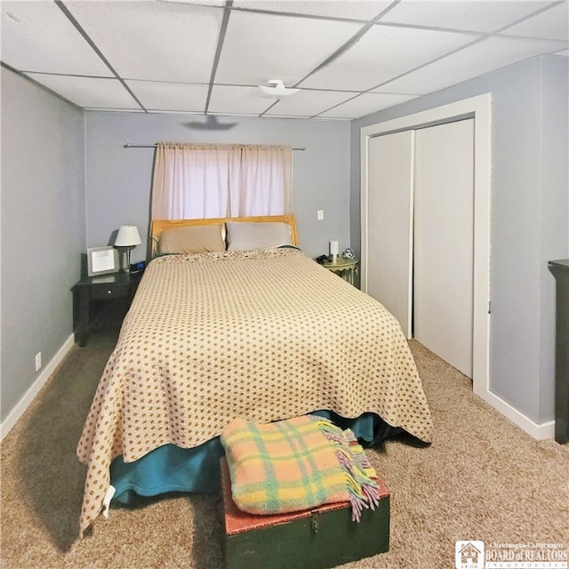 carpeted bedroom with a paneled ceiling and a closet