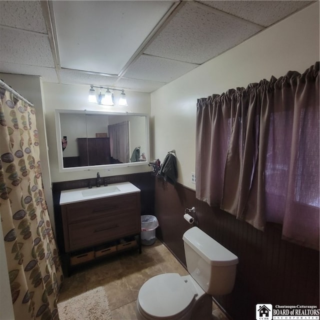 bathroom with vanity, a paneled ceiling, toilet, and tile patterned flooring